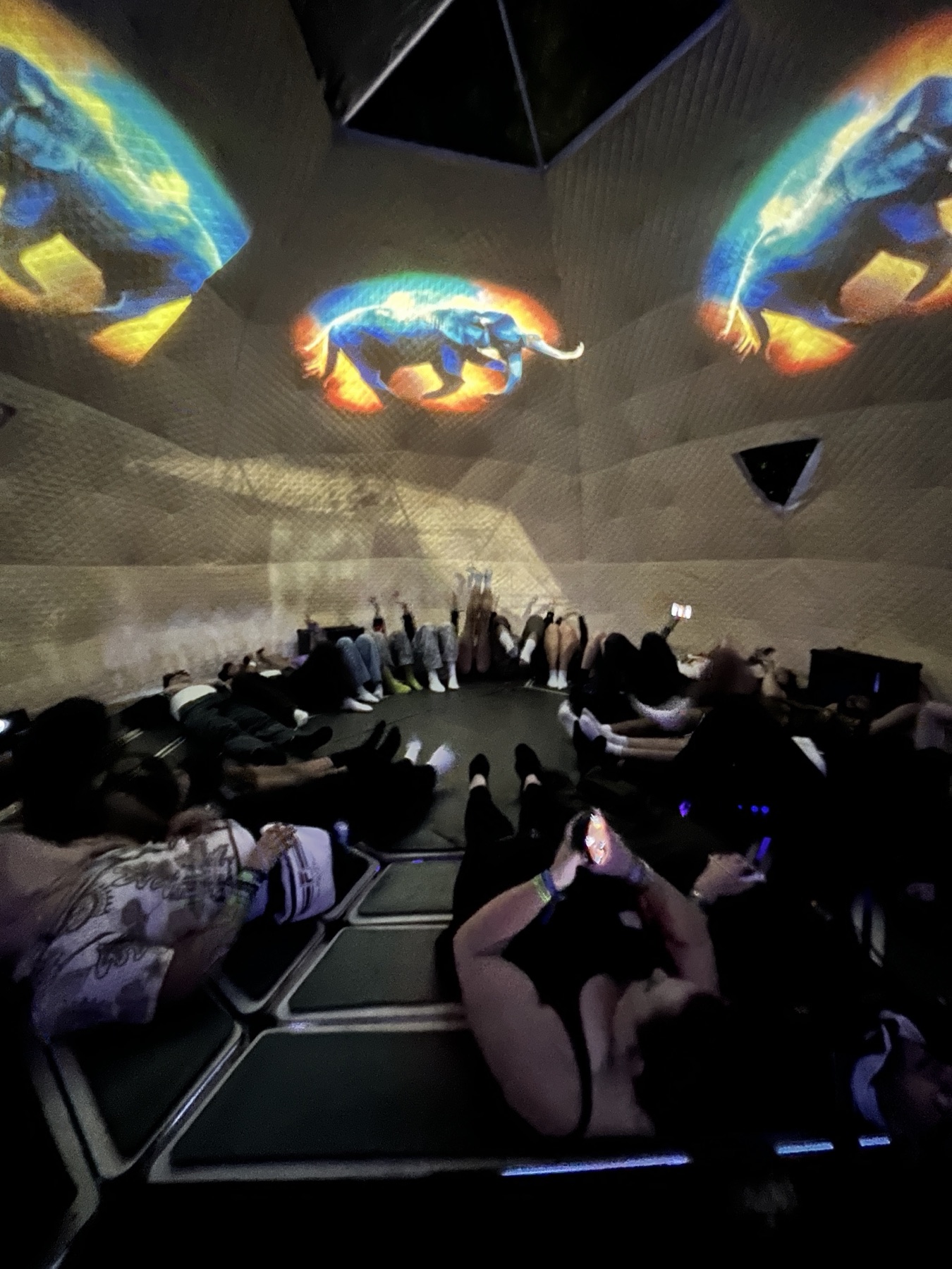 SoundTemple at Experts Only Festival in 2025: listeners reclining on transducer beds while ETHEREA's colorful animal projections fill the walls and ceiling.